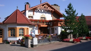 Tipico chalet con tetto in tegole rosse, balconi in legno e fioriere.