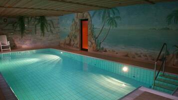 Ein Hallenbad mit gefliesten Wänden und einer Wandmalerei einer Strandlandschaft.