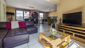 Uma sala de estar moderna com um sofá de couro, uma mesa de centro e uma televisão de tela plana.