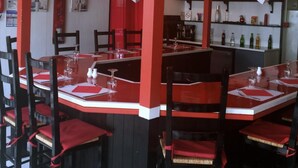 Ein Restaurant mit roter und weißer Einrichtung, runden Tischen und schwarzen Stühlen.