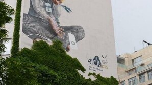 A tall building with a mural of an astronaut holding a flower. - Tiflisi Guest House - Hostel (Tbilisi)