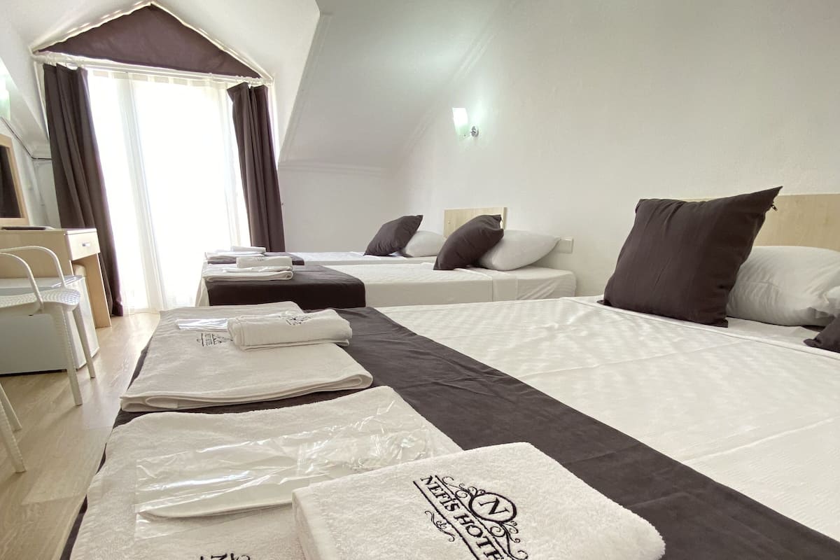A hotel room with two beds, a desk, a chair, and a bathroom visible through a door.