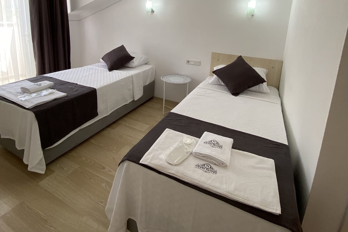 A hotel room with two beds, a small round table, and a ceiling fan.