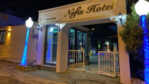 The exterior of the Nefis Hotel with a reception area, illuminated entrance, and decorative street lamps.