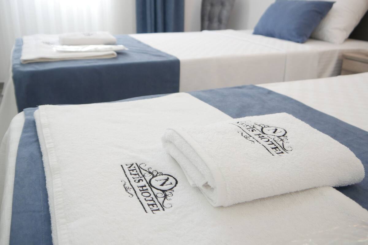 Two hotel beds with neatly folded white towels and a blue bedspread.