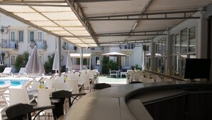 An outdoor pool area with lounge chairs and umbrellas, surrounded by tables and chairs, with a view of a building in the background. - Nefis Hotel Oludeniz (Fethiye)