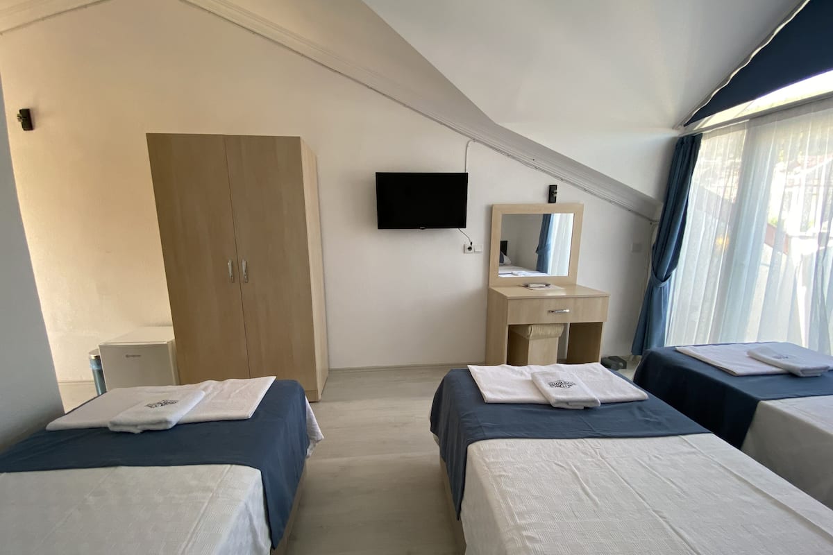 A hotel room with two beds, a wardrobe, a desk with a mirror, and a TV mounted on the wall.