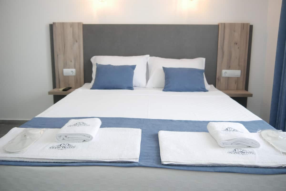 A hotel room with a large bed, two bedside tables, and two wall-mounted lights.
