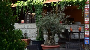 An outdoor seating area with a table and chairs, surrounded by potted plants and a bonsai tree. - Aux Bords Du Temps (Zonza)