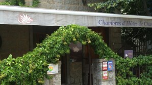 A hotel entrance with a stone archway covered in greenery, a sign for 'Chambres d'Hôtes de Char', and a plaque indicating '2014'. - Aux Bords Du Temps (Zonza)