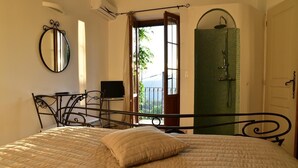 A bedroom with a bed, a desk, a mirror, and a view of the outdoors. - Aux Bords Du Temps (Zonza)