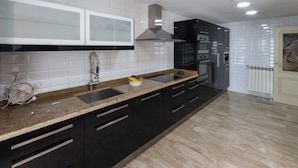 Eine moderne Küche mit schwarzen Schränken, einer Granit-Arbeitsplatte und einer Edelstahl-Dunstabzugshaube.