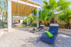 A covered outdoor seating area with lounge chairs and a table, surrounded by palm trees and a pergola. - CAN ESTELRICH- SANT BLAI - Chalet for 4 people in Campos. Free WiFi (Campos)