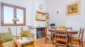 Un comedor con una mesa redonda, sillas, una chimenea y una ventana con vistas.
