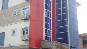 Een hotel met een gevel in rood en beige, meerdere balkons en een bord dat aangeeft dat het een hotel is.