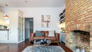 A living room with a leather sofa, a glass coffee table, and a brick fireplace. - Vauxhall Park Views - 2 Bed Flat by BaseToGo (London)