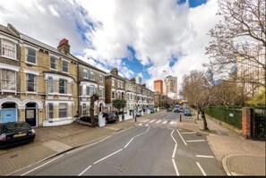 A residential street with terraced houses, a clear sky, and a pedestrian crossing. - Vauxhall Park Views - 2 Bed Flat by BaseToGo (London)