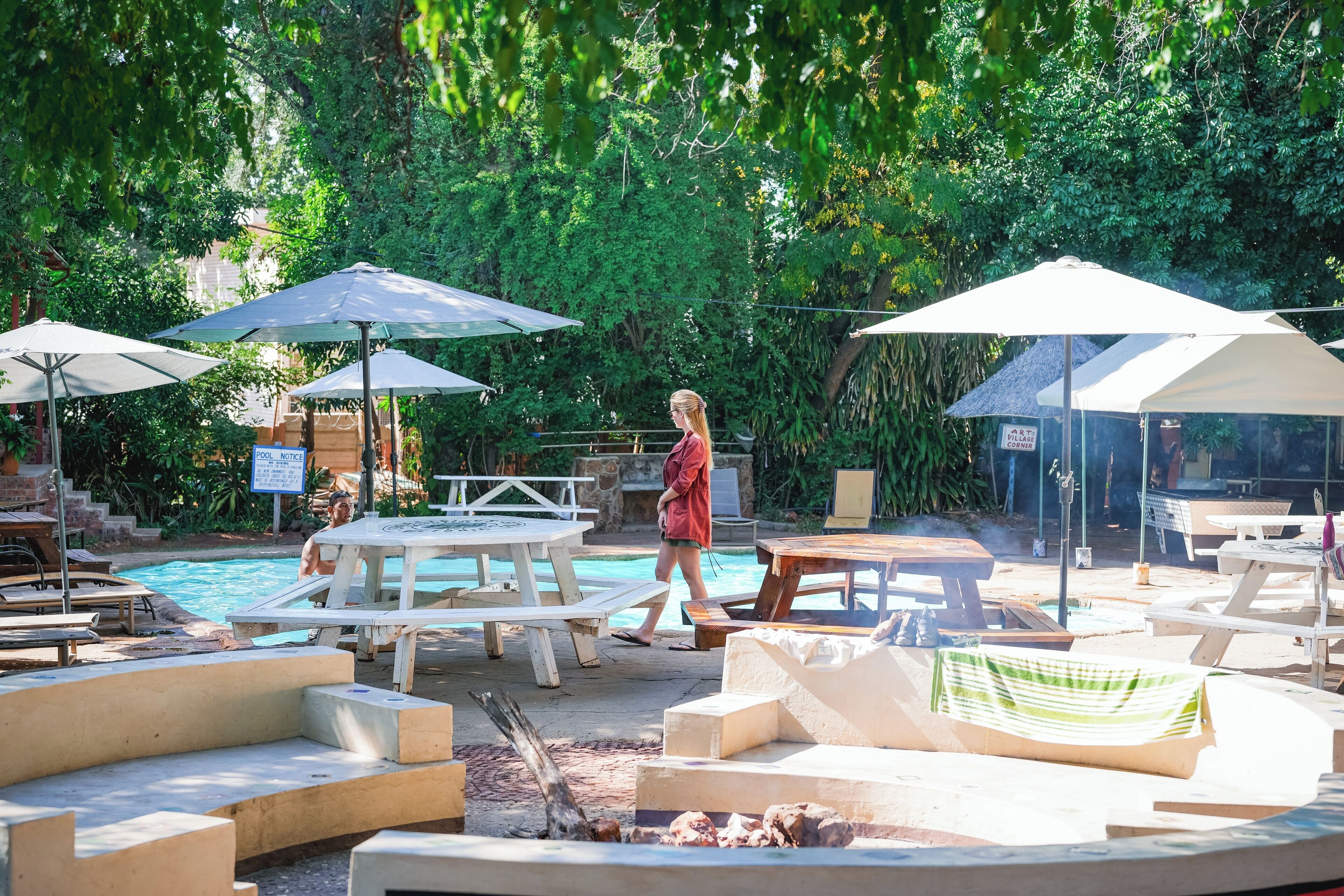 A poolside area with lounge chairs, umbrellas, and a fire pit.