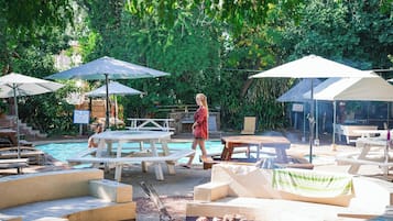 A poolside area with lounge chairs, umbrellas, and a fire pit.