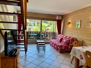 Een kamer met balkon, een bank, een tafel en een televisie.
