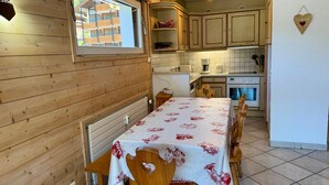 A wooden interior with a dining table, chairs, a kitchen area, and a window. - 2-Bedroom Duplex near Ski Slopes, Central Village, Parking, Balcony, La Clusaz (La Clusaz)