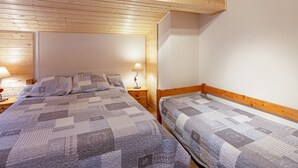 Un dormitorio con dos camas individuales, techo de madera y lámparas de noche.