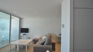 Un salon moderne avec un canapé, un téléviseur et un mur en verre.