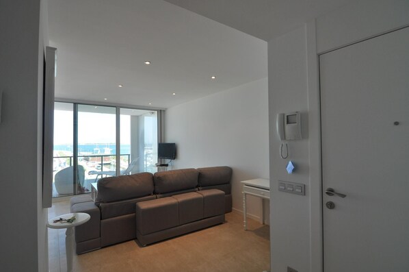 Een moderne woonkamer met een bank, een kleine tafel, een televisie en een deur met slot.
