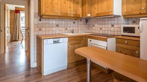 A kitchen with wooden cabinets, a dishwasher, a microwave, and a tiled backsplash.