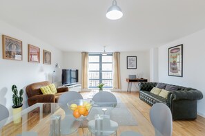 Un salon moderne avec une table à manger en verre, un canapé en cuir et un téléviseur.