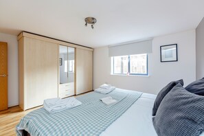 A bedroom with a bed, a wardrobe, a window, and a framed picture on the wall. - The Bateman's Shoreditch 2 Bed Flat by BaseToGo (London)