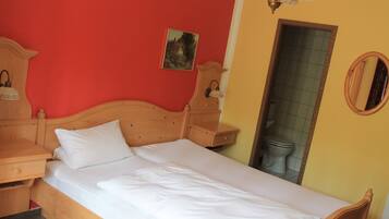 A single bed with a wooden headboard, a bedside table, a nightstand, and a wall-mounted lamp.