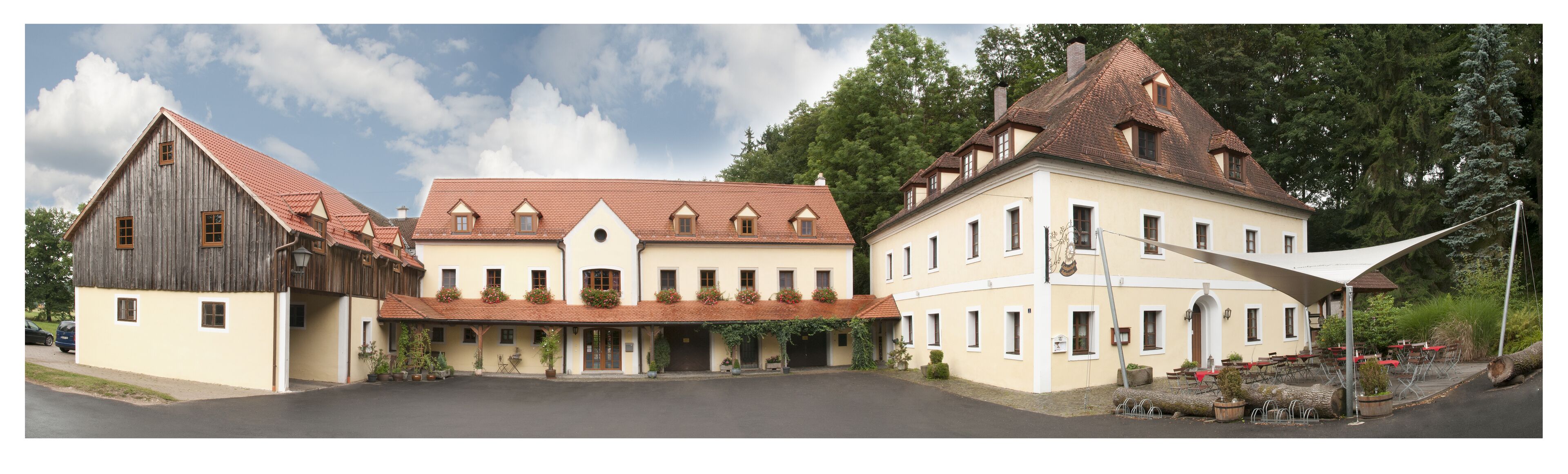 Een traditioneel Europees gebouw met een centrale binnenplaats, met een combinatie van houten en stukgepleisterde gevels, en een overdekt terras.