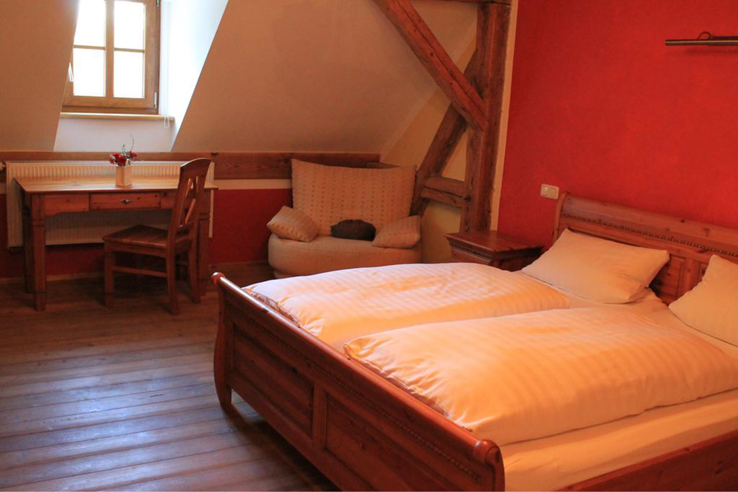 Un dormitorio con una cama de madera, un escritorio y una silla.