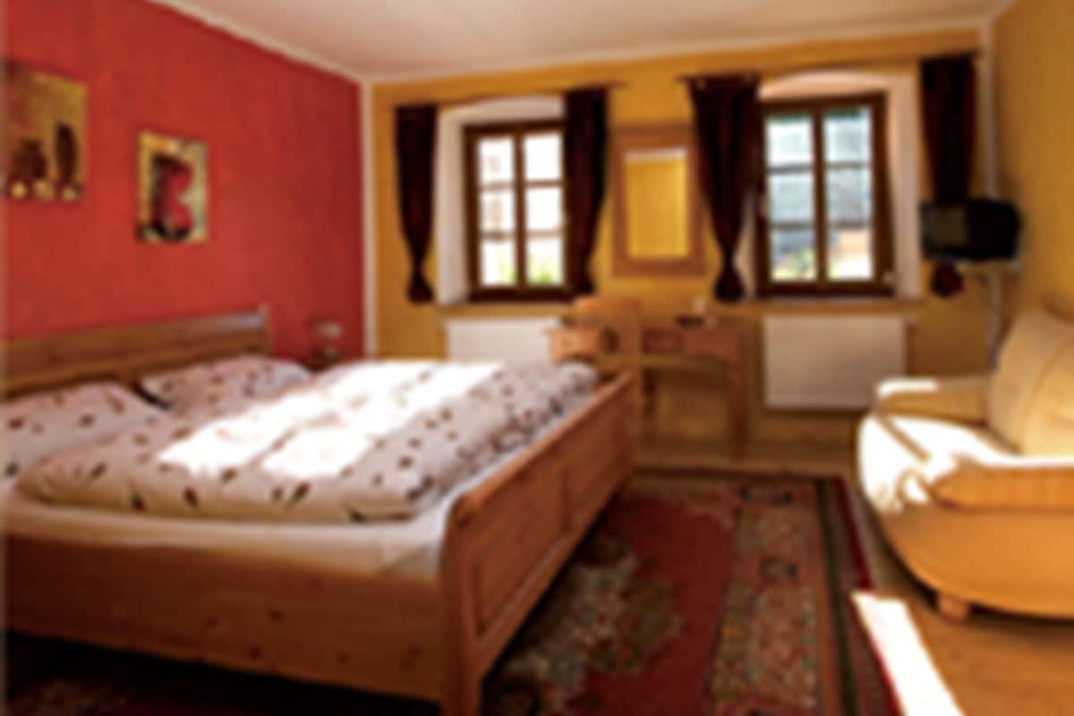 Een slaapkamer met een bed, een stoel, een bureau en een raam.