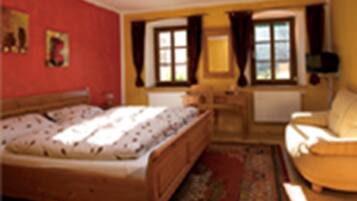 A bedroom with a bed, a chair, a desk, and a window.