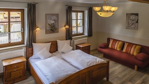 Un dormitorio con una cama de madera, un sofá rojo y dos mesitas de noche.