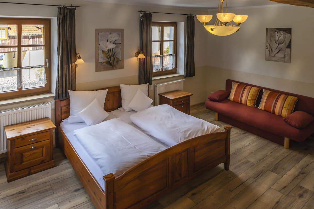 Een slaapkamer met een houten bed, een rode bank en twee nachtkastjes.