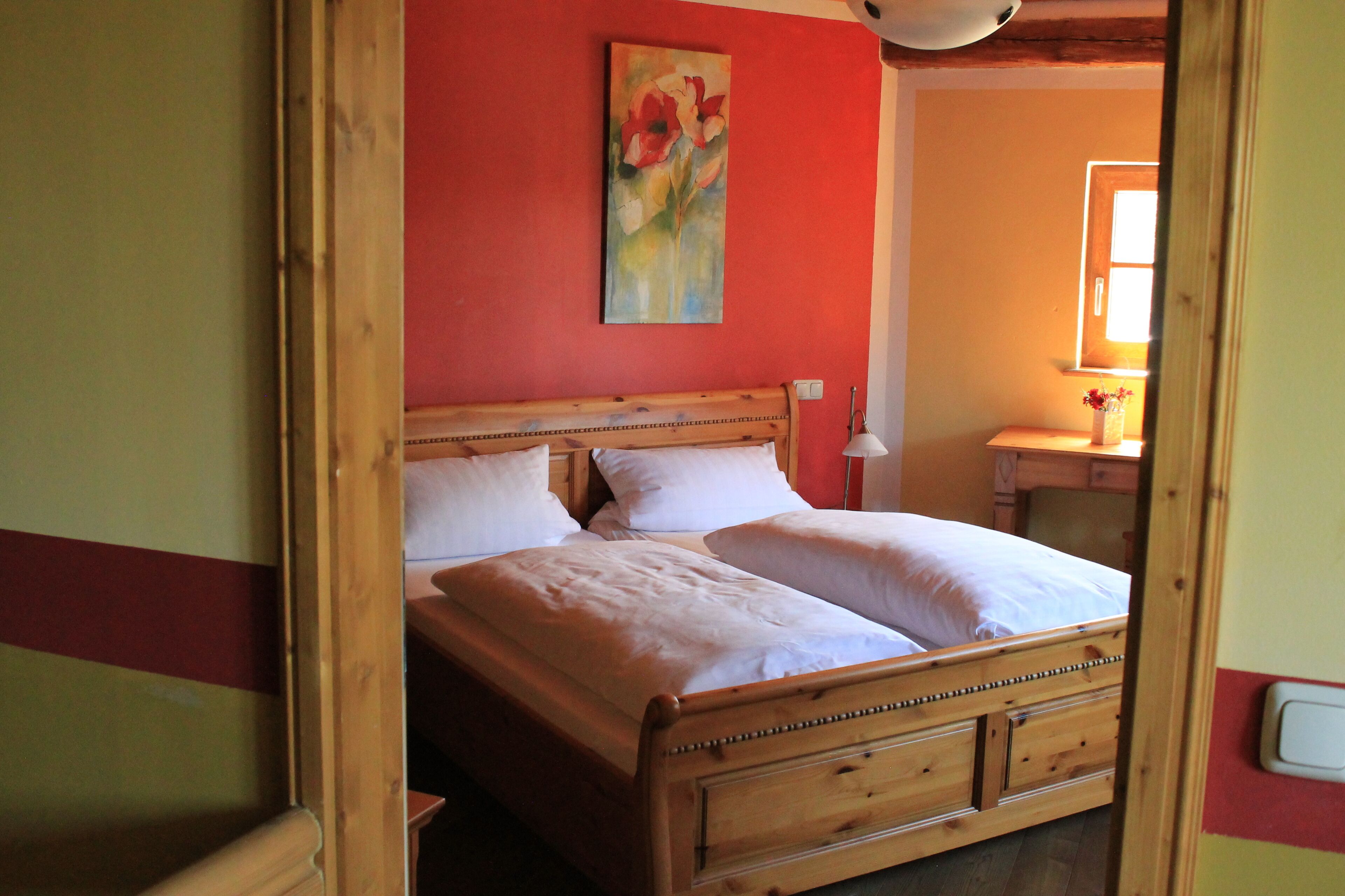Una cama de madera con dos almohadas y una mesita de noche con una lámpara.