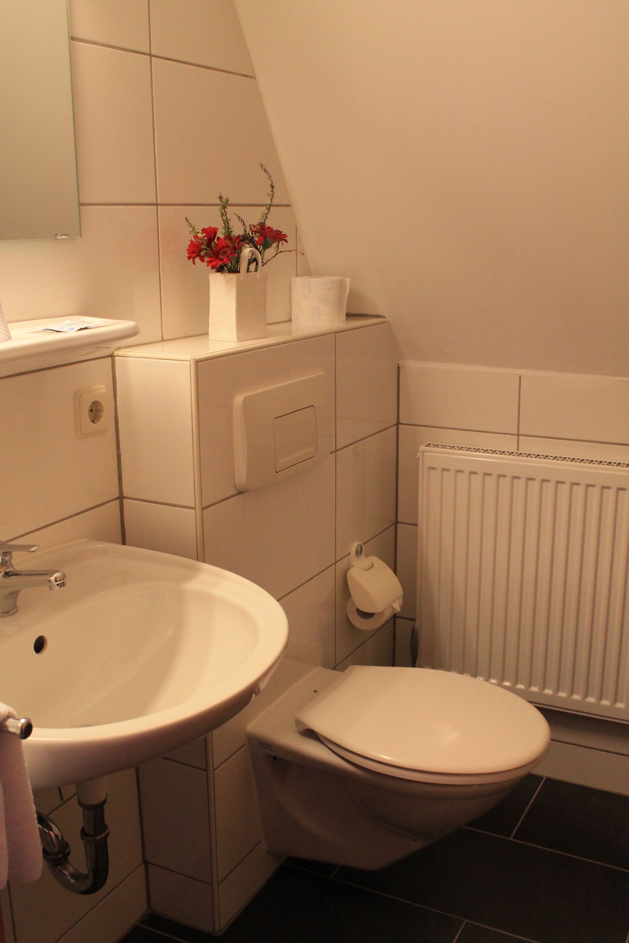 A bathroom with a white sink, toilet, and radiator.