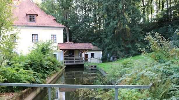 Una casa con techo rojo y un pequeño muelle que se adentra en un estrecho canal.