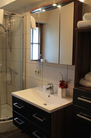 Driepersoonskamer, privébadkamer | Badkamer | Een douche, een haardroger, handdoeken, zeep
