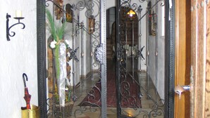 Un vestíbulo con puerta de vidrio, un paraguas de bronce y un banco de madera.