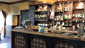 A bar area with a counter, shelves with bottles, and a chalkboard menu. - Calf's Head Hotel (Clitheroe)
