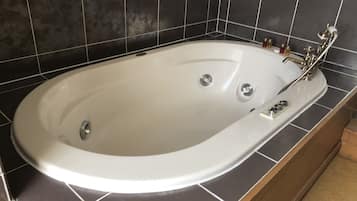 A white bathtub with a single faucet and two drains, set against a tiled wall.