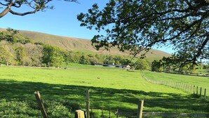 A stone pathway leading through a grassy field with a wooden fence and a metal gate. - Calf's Head Hotel (Clitheroe)