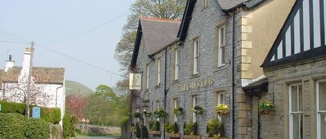 A stone building with a sign that reads "The Old Mill." It has a traditional architectural style with a pitched roof and multiple windows.