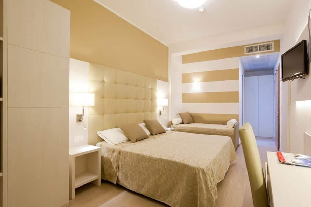 Habitación de hotel con dos camas, televisión y escritorio.