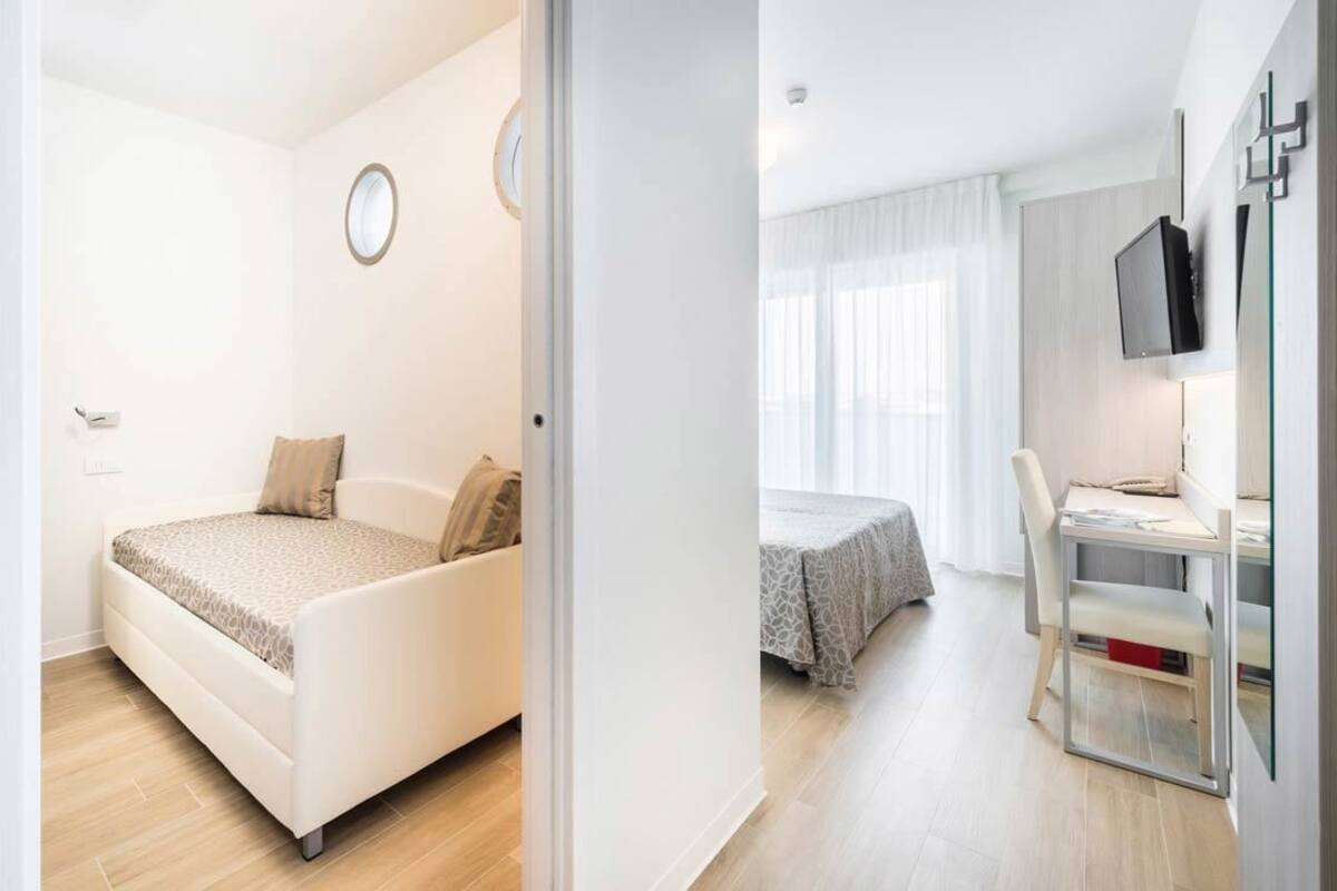 Un dormitorio moderno con cama, mesita de noche y televisor montado en la pared.