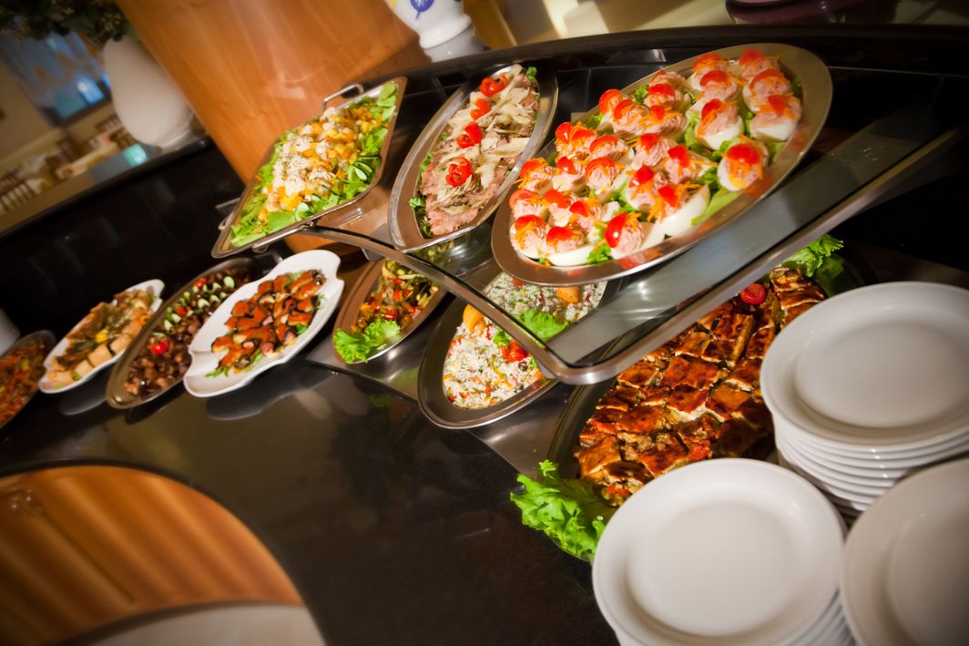 Un bufé con diversos platos, incluyendo sushi, ensaladas y carnes a la parrilla.